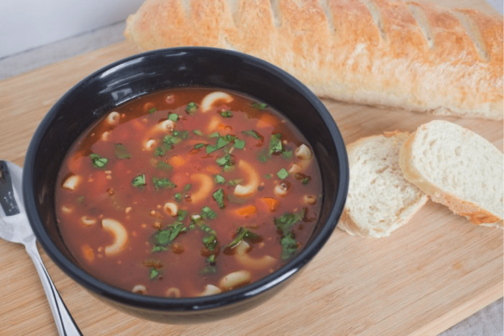 Italian noodle soup in bowl with spoon and French bread. 