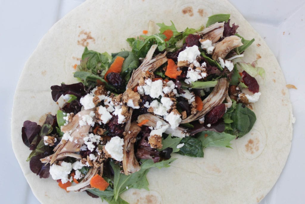 chicken, greens, cheese and lettuce in a tortilla