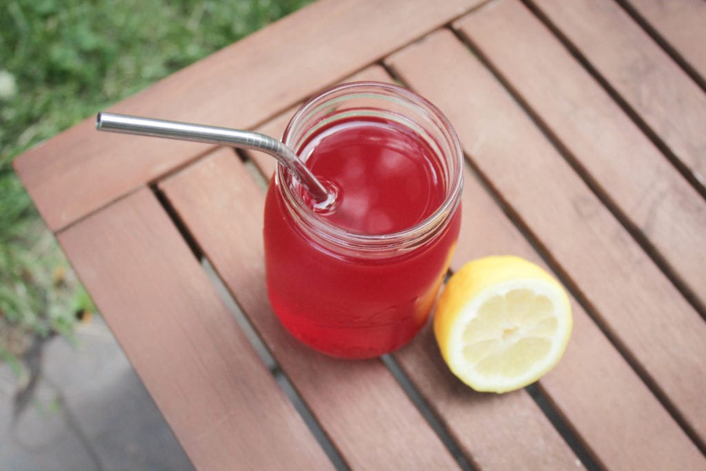 passion tea lemonade in ball jar with metal straw and cut up lemon