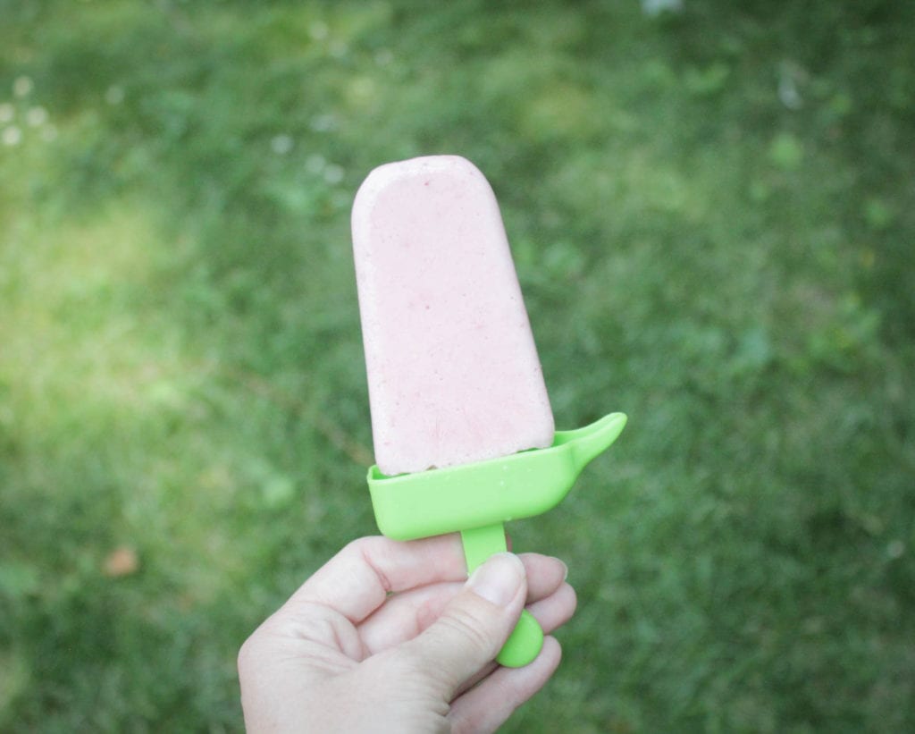 Woman holding a strawberry cheesecake popsicle 