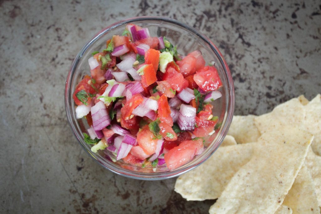 Fresh pico de gallo in glass bowl with tortilla chips