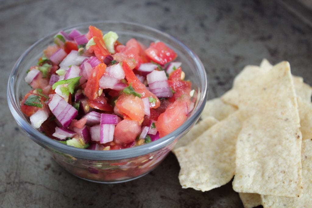 Pico de gallo in a glass bowl with tortilla chips