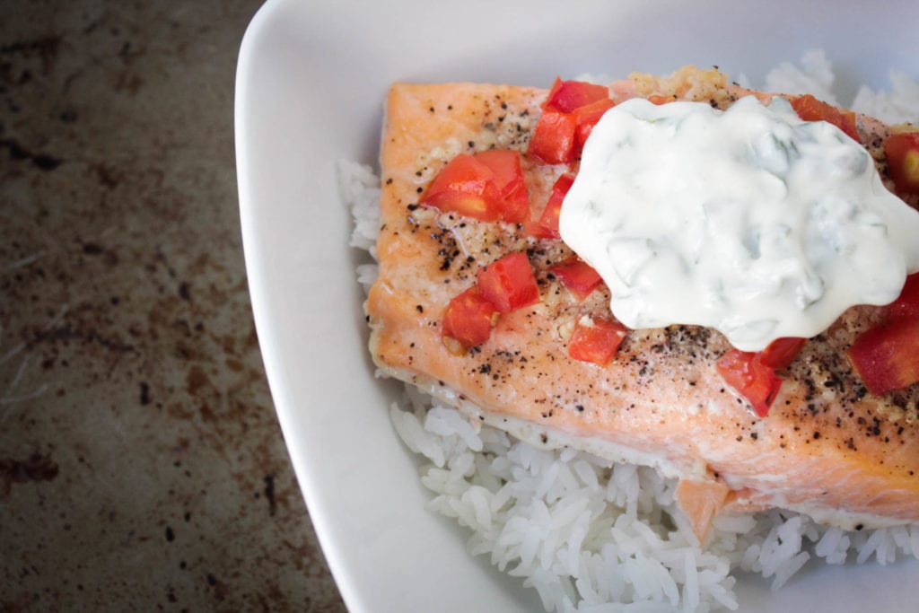 baked salmon with tomatoes and basil mayo over rice in a white bowl
