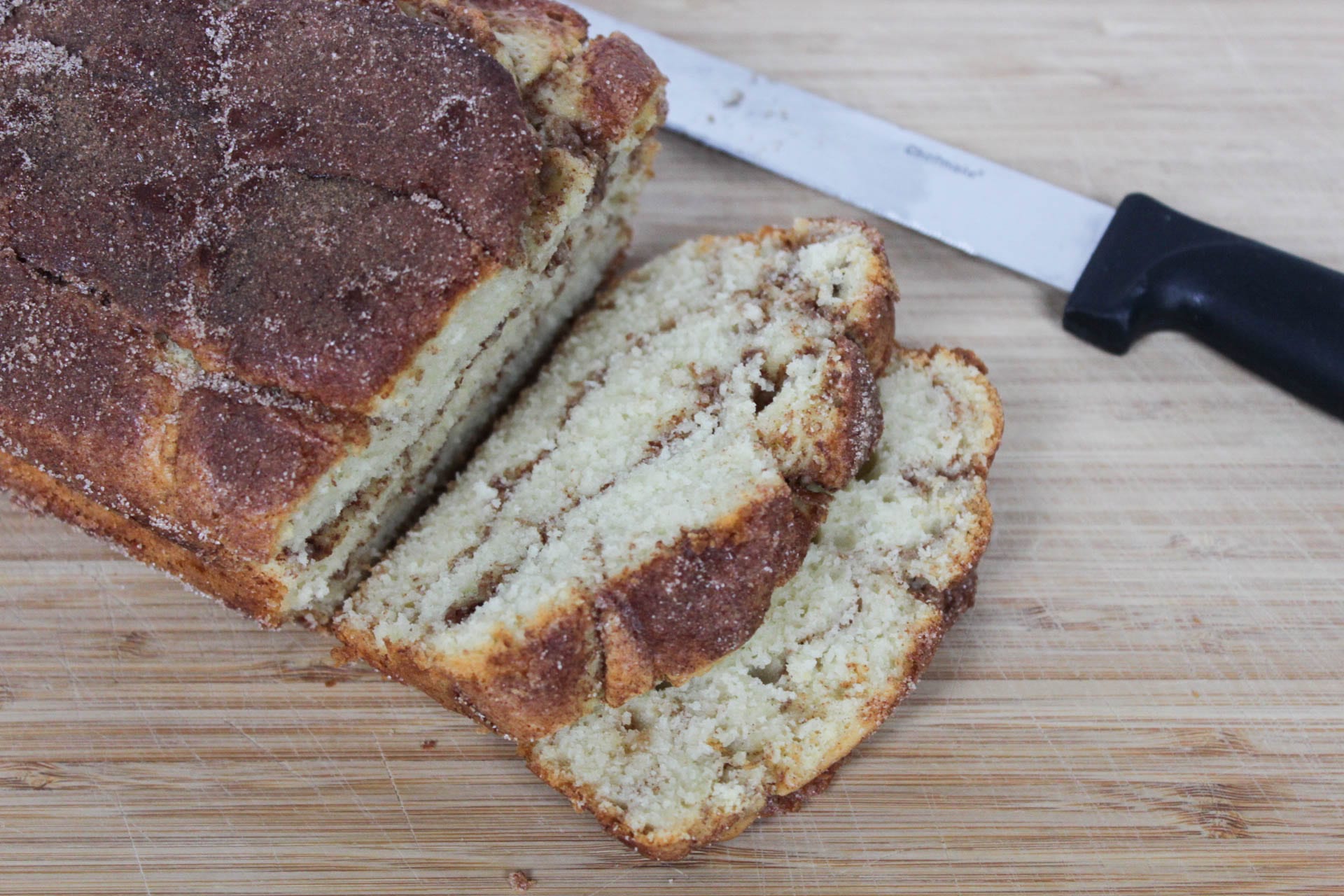 Sliced cinnamon loaf bread on cutting board with knife in background
