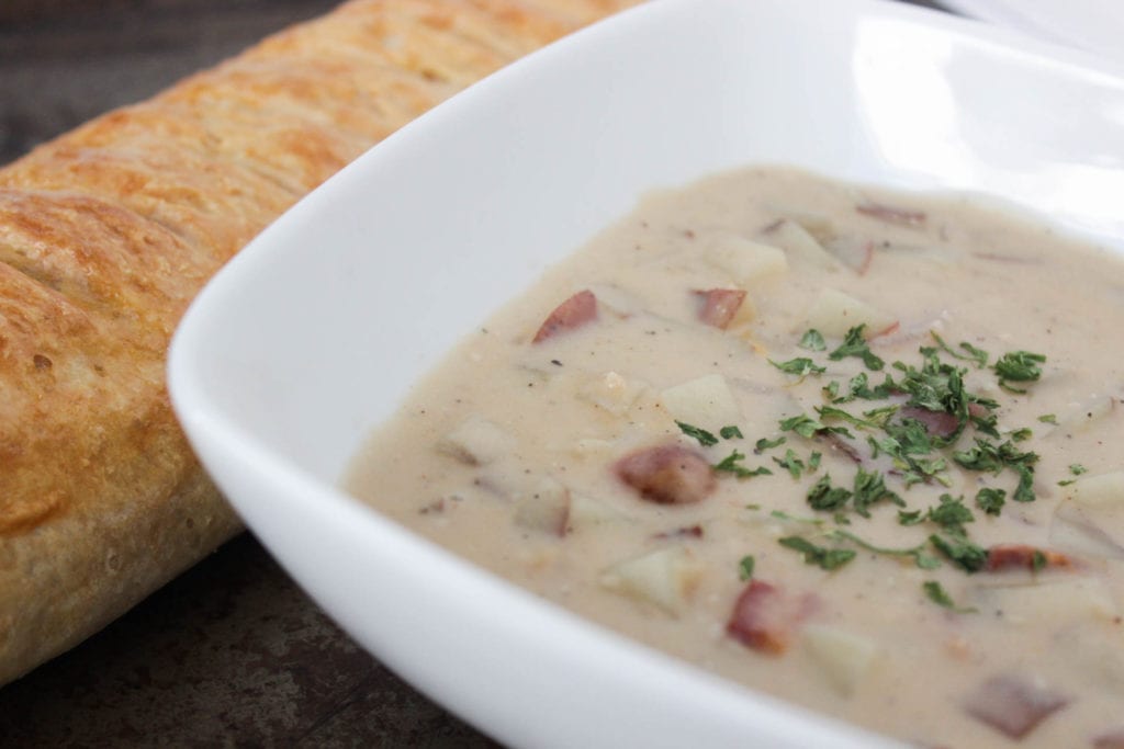 Creamy potato soup in bowl with french bread