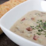Creamy potato soup in bowl with french bread