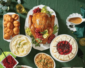 Turkey, mashed potatoes, rolls, cherry pie, cranberry sauce, stuffing and gravy on green tablecloth