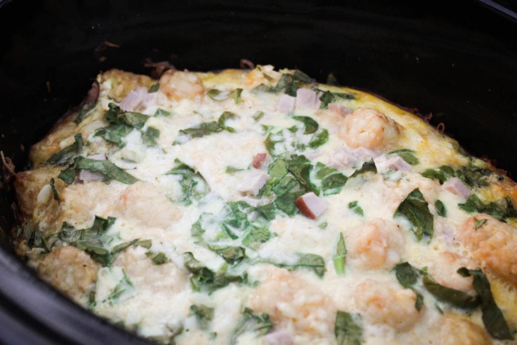 Egg casserole with ham, cheese, tater tots, spinach and onion made in the slow cooker