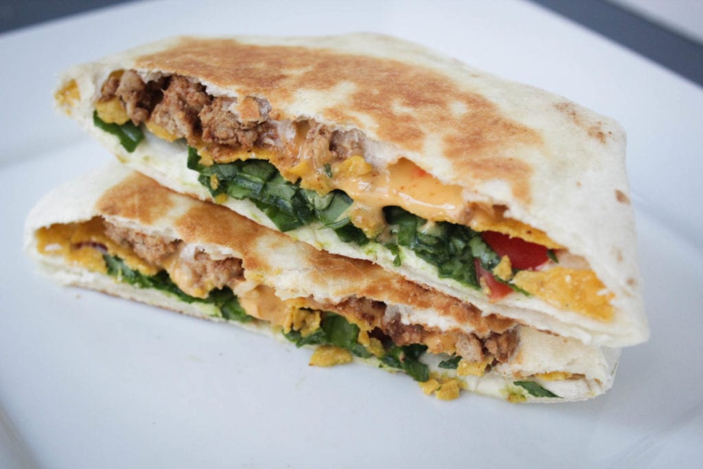 crunchwrap supreme copycat recipe with taco meat, cheese, tomatoes, sour cream, spinach and toasted in a burrito