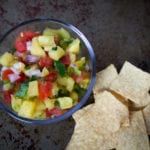 Bowl of pineapple salsa with fresh pineapple, tomatoes, red onion, jalapeno, cilantro and lime served with chips