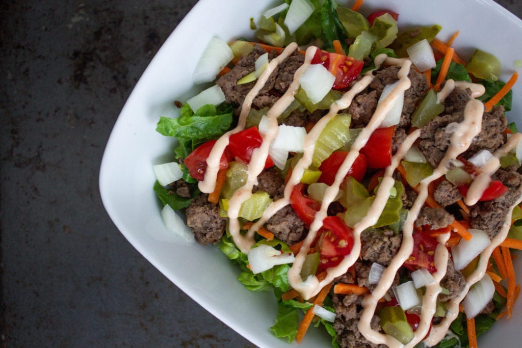 big mac salad with lettuce, tomatoes, ground beef, diced pickles, shredded carrots, white onions and drizzled with thousand island