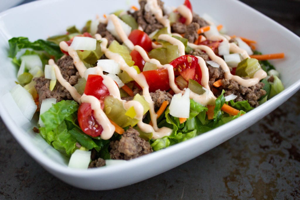 big mac salad with lettuce, tomatoes, ground beef, diced pickles, shredded carrots, white onions and drizzled with thousand island