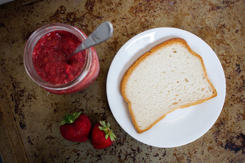 jar of strawberry jam and piece of white bread