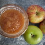homemade pressure cooked applesauce in a jar on a table next to 3 apples