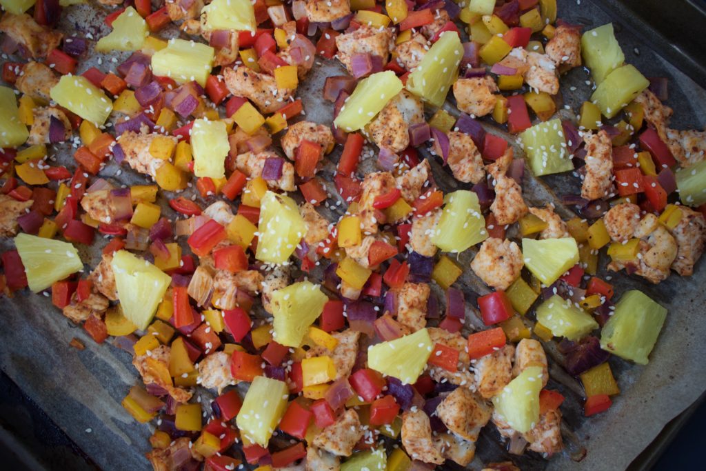 Hawaiian BBQ Chicken with diced bell peppers, onions, and pineapple on a sheet pan