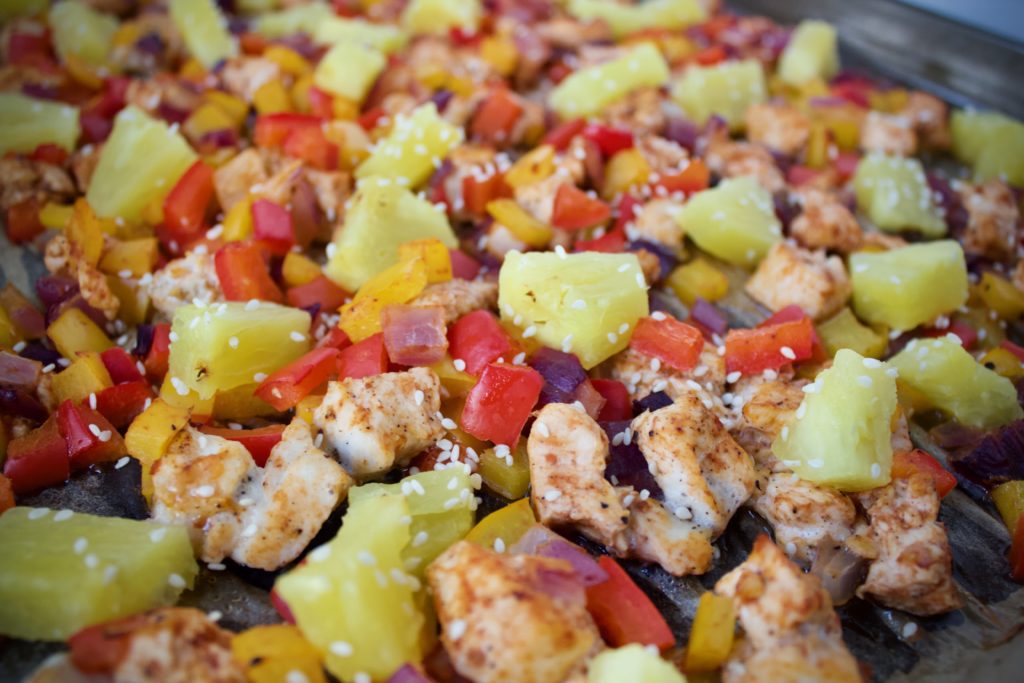 Hawaiian BBQ Chicken with diced bell peppers, onions, and pineapple on a sheet pan