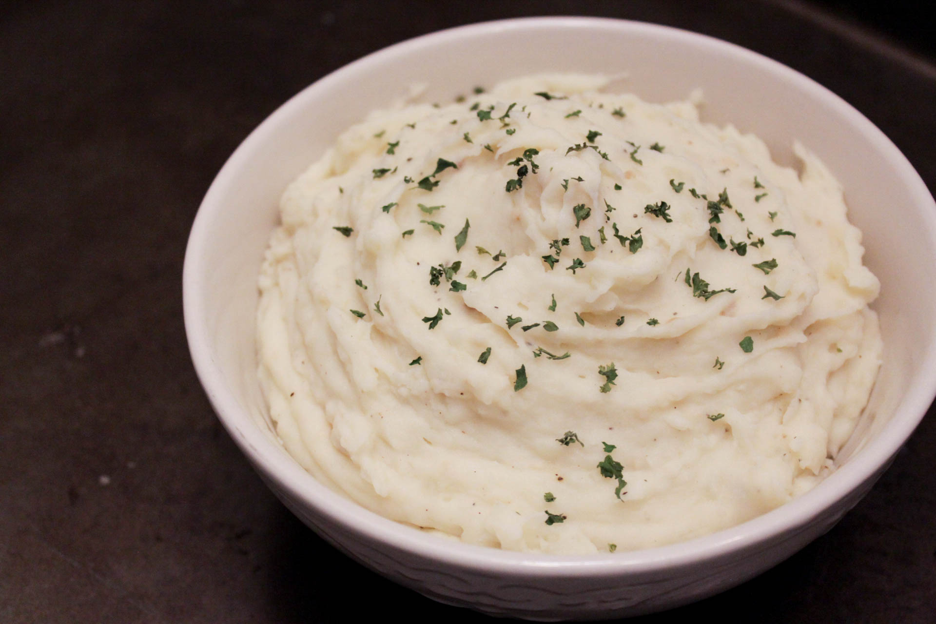 bowl of mashed potatoes topped with dried parsley