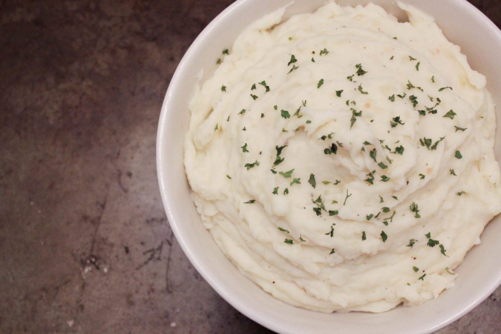 bowl of mashed potatoes topped with parsley