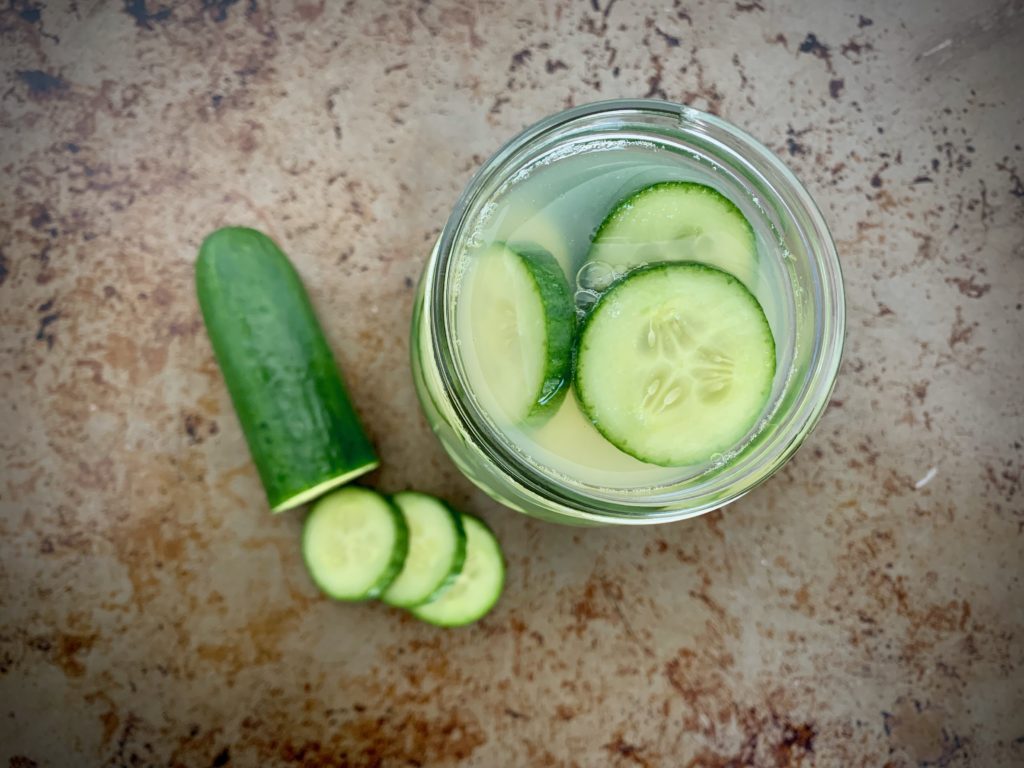 Top down view of glass jar with sliced pickles