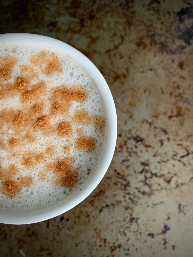 Cinnamon Maple oatmilk latte with cinnamon sprinkled on top in a white mug