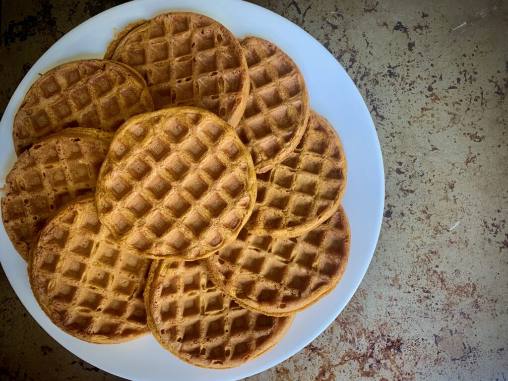 9 sweet potato waffles fanned out on a white plate