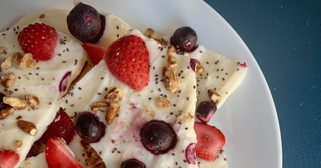 berry yogurt bark with fresh blueberries and strawberries on a white plate