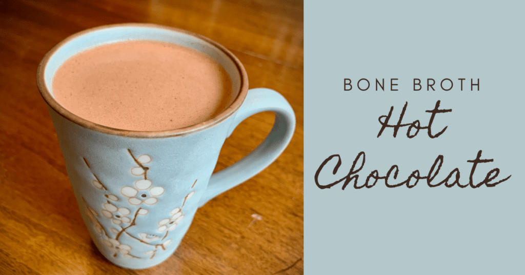 bone broth hot chocolate in light blue mug with white flowers sitting on wood counter