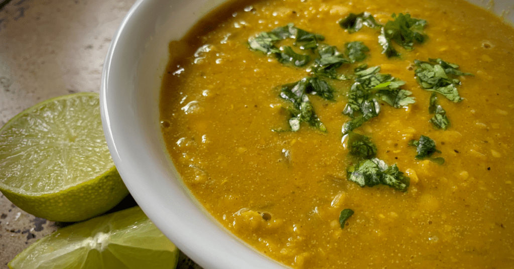 A white bowl with curry lentil sopu and cilantro. 