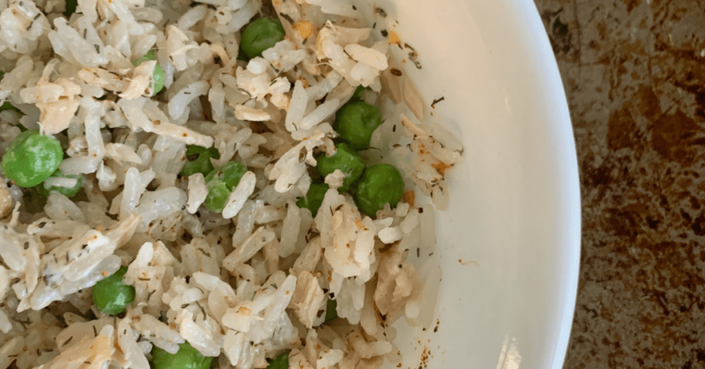 white bowl with white rice, tuna, and peas.