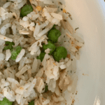 white bowl with white rice, tuna, and peas.