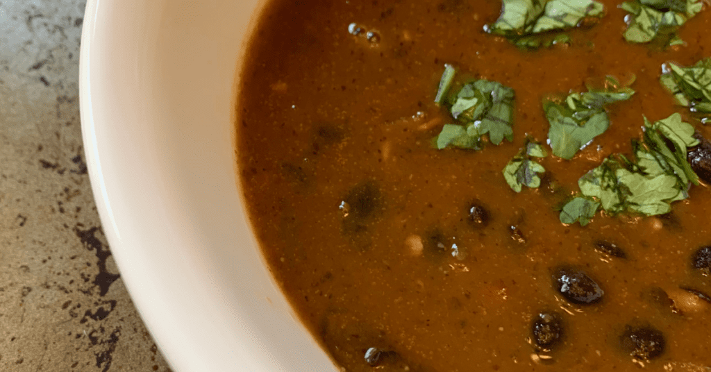 white bowl with creamy black bean soup and cilantro