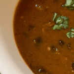 white bowl with creamy black bean soup and cilantro